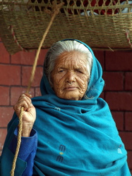 Alte Nepalesin - mit dem Seil hält sie die Kinderwiege in Bewegung